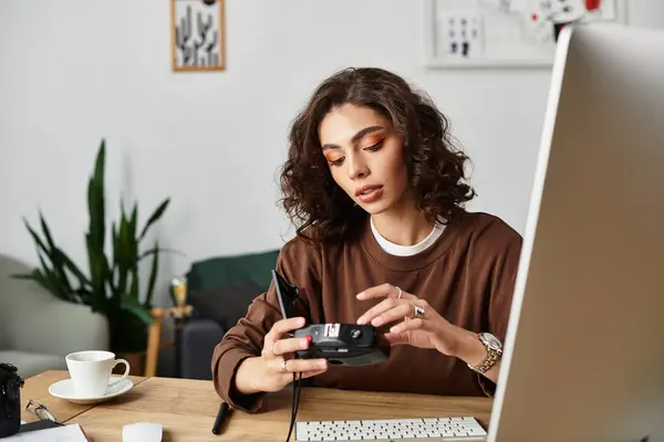 Young woman with curly hair focuses on her camera while working from a stylish home office. — Stock Photo