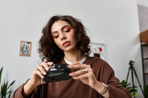 A young woman with curly hair focuses on her camera as she works remotely in her home office. — Stock Photo