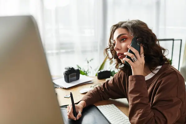 Young woman with curly hair focuses on editing work using a graphic tablet and stylus pen. — Stock Photo