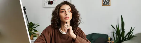 A young woman with curly hair contemplates her next creative move while working remotely, banner — Stock Photo