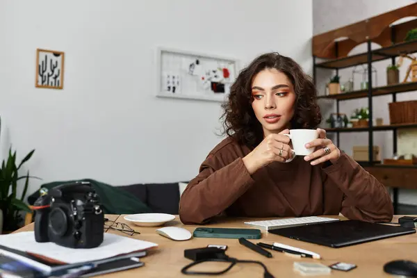 Young woman sips coffee while focused on her work in a stylish home office setup. — Stock Photo