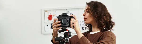 Young woman with curly hair engages with her camera, dedicated to her remote photography work, banner — Stock Photo
