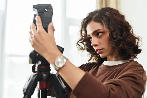Curly-haired woman sets up her camera, aiming to capture the perfect shot at home. — Stock Photo
