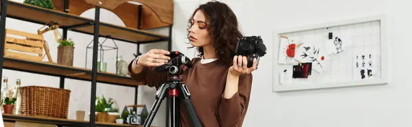 A young woman with curly hair sets her camera on a tripod in her cozy home studio, banner — Stock Photo