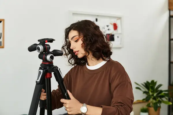 A talented woman with curly hair adjusts her camera gear while freelancing from home. — Stock Photo