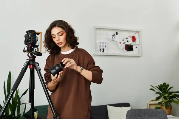 Young woman prepares her camera while working from her cozy home office setup. — Stock Photo