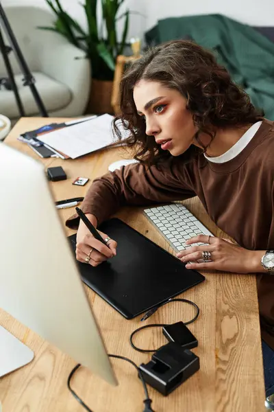 A young woman edits digital art at her home workspace with a graphic tablet. — Stock Photo