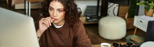 Young woman with curly hair focuses intently on her work in a stylish home office, banner — Stock Photo