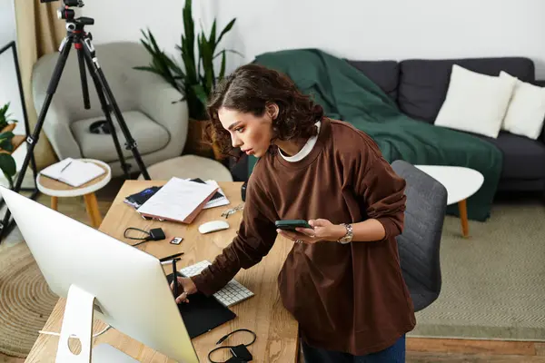 Young woman with curly hair deeply engaged in retouching with a graphic tablet at home. — Stock Photo