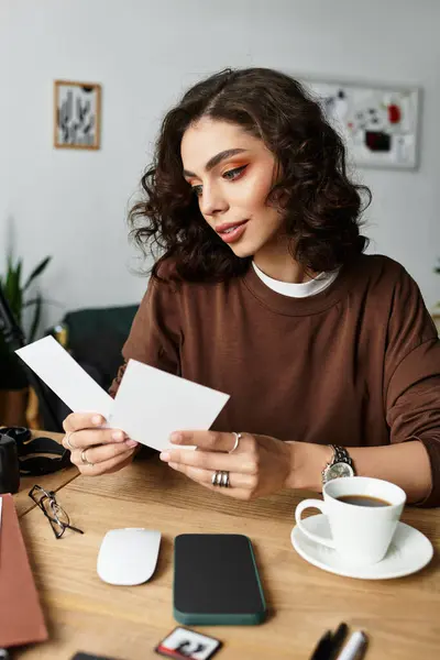 A young woman with curly hair engages with her printed photography — Stock Photo