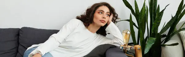 Curly-haired woman relaxes in her chic, plant-filled apartment, banner — Stock Photo