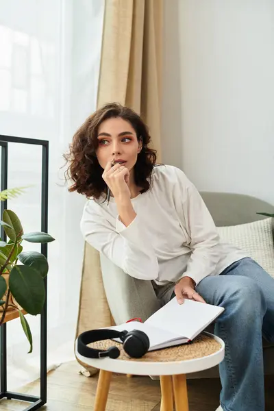 A young woman with curly brown hair enjoys a moment of rest while seated in her cozy apartment. — Stock Photo