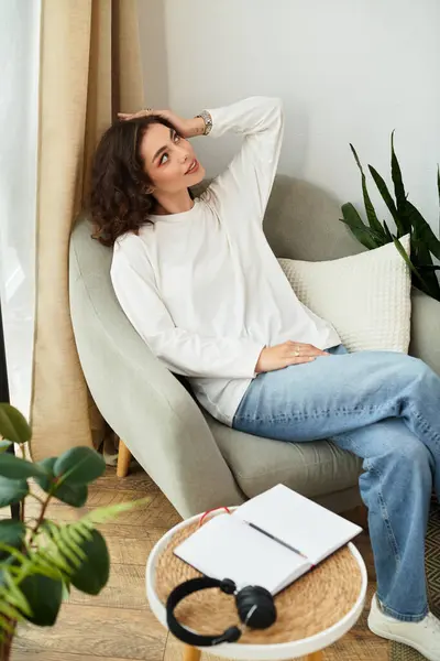 A young woman with curly brown hair finds peace while resting comfortably in her stylish apartment. — Stock Photo