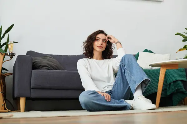 Curly brown haired girl relaxes in a modern apartment, surrounded by cozy decor and plants. — Stock Photo