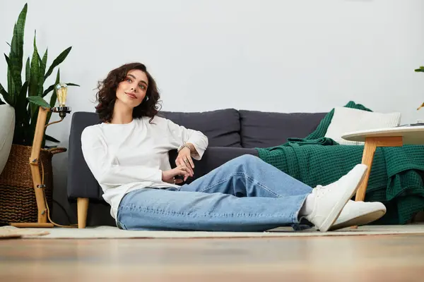 A young woman with curly brown hair relaxes in her chic apartment, enjoying tranquility. — Stock Photo