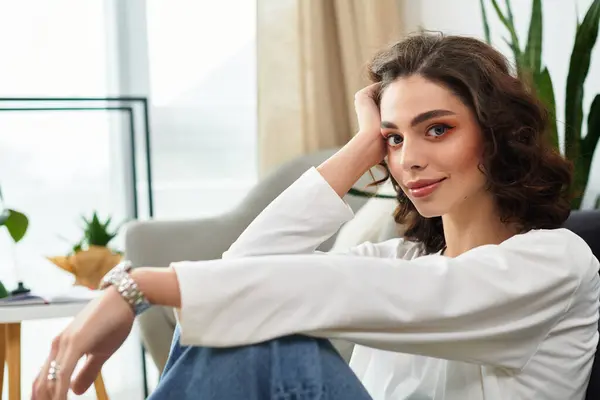 Young woman with curly brown hair finds serenity in her modern living space, embracing calm. — Stock Photo