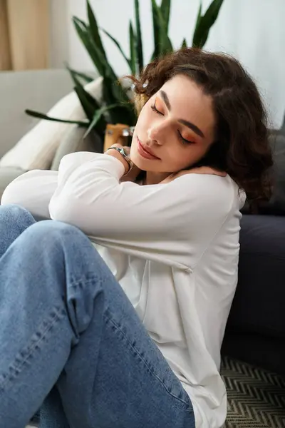 Curly brown-haired woman relaxes in a cozy, modern apartment while lost in thought. — Stock Photo