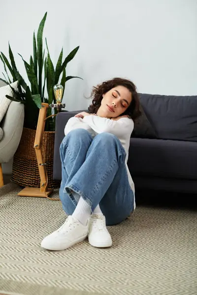 A beautiful young woman sits comfortably, taking time to rest in her cozy home. — Stock Photo