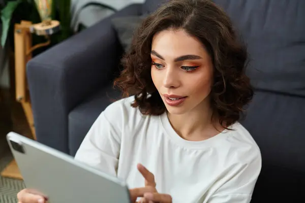 A beautiful young woman with curly brown hair is comfortably resting in her modern apartment. — Stock Photo