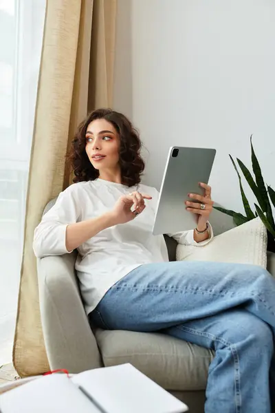 Young woman with curly brown hair enjoys a moment of leisure in her stylish living space. — Stock Photo