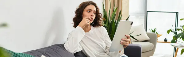 A young woman relaxes in her stylish apartment while engaging with a tablet, banner — Stock Photo