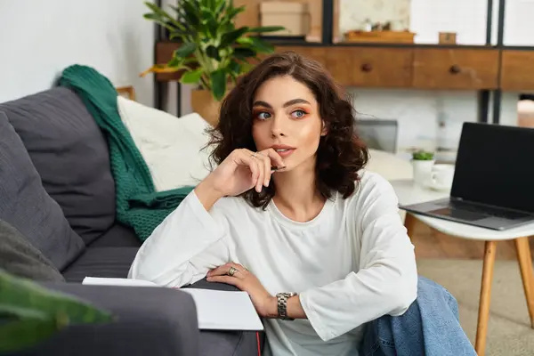 Young woman with curly hair enjoys working from home in a stylish and comfortable setting. — Stock Photo