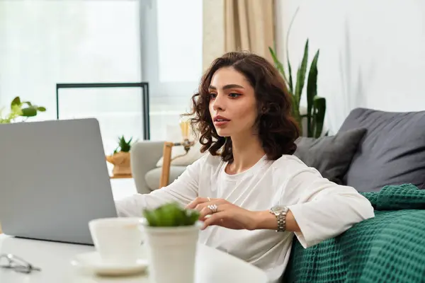 Young woman with curly hair focused on freelance work at home in a cozy setting. — Stock Photo