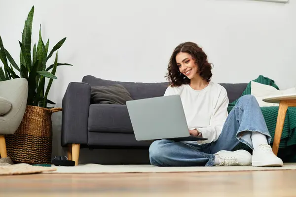 Young woman with curly hair focused on her laptop in a relaxed home environment. — Stock Photo