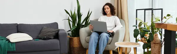 A young woman with curly hair focuses on her laptop while enjoying her remote workspace, banner — Stock Photo