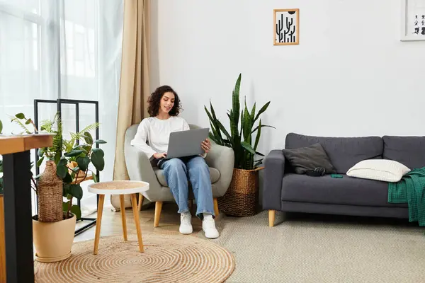 Curly-haired freelancer engages in remote work while seated comfortably in her stylish home office. — Stock Photo