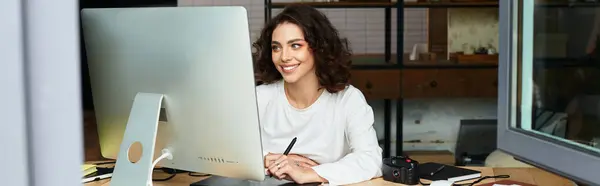 Young woman with curly hair focused on editing artwork in her cozy home workspace, banner — Stock Photo