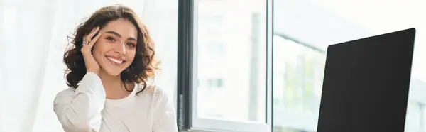 A cheerful young woman with curly hair radiates positivity while working from home, banner — Stock Photo