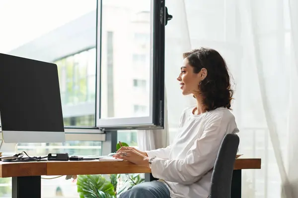 A dedicated freelancer with curly hair is immersed in her work at home, enjoying a bright workspace. — Stock Photo