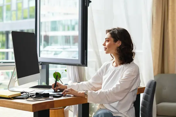 Young woman with curly hair works on retouching images using a graphic tablet in her home office. — Stock Photo