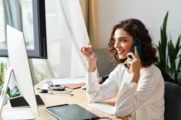 Young woman with curly hair is happily editing images at her home workspace using a graphic tablet. — Stock Photo
