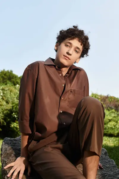 Curly-haired young man relaxes in a vibrant park, embracing summer's warm atmosphere. — Stock Photo