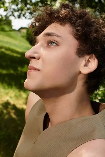 Curly-haired young man relaxes in a vibrant park, embracing sunny summer vibes with style. — Stock Photo