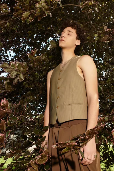 Curly-haired young man relaxes amidst the greenery, showcasing trendy summer fashion vibes. — Stock Photo
