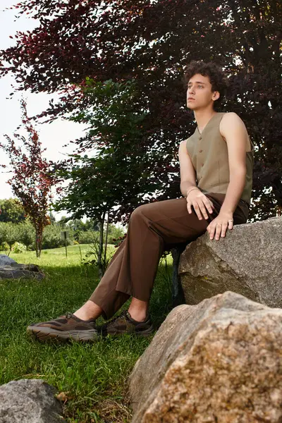 Sunlight showcases a young man's stylish summer outfit as he relaxes in the park. — Stock Photo