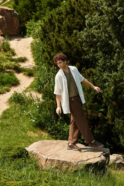 Young man in casual summer outfit explores a lush green park while enjoying the outdoors. — Stock Photo