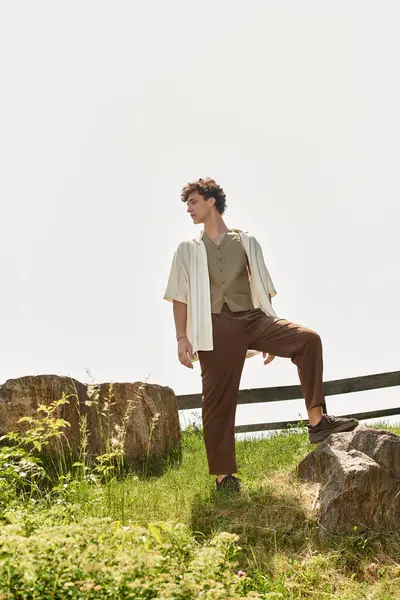 A stylish young man in a summer outfit relaxes in a lush green park surrounded by nature. — Stock Photo