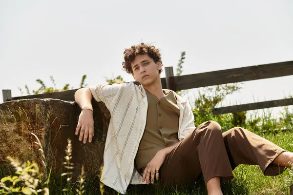 A young man with curly hair relaxes in a vibrant park, embracing summer fashion and charm. — Stock Photo