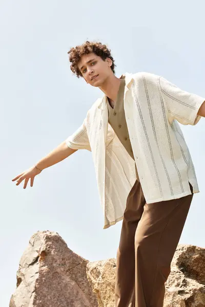 A young man with curly hair rocks a stylish summer outfit in a lush park. — Stock Photo
