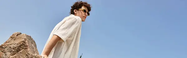 A stylish young man with curly hair relaxes outdoors in a vibrant park during sunny summer days, banner — Stock Photo