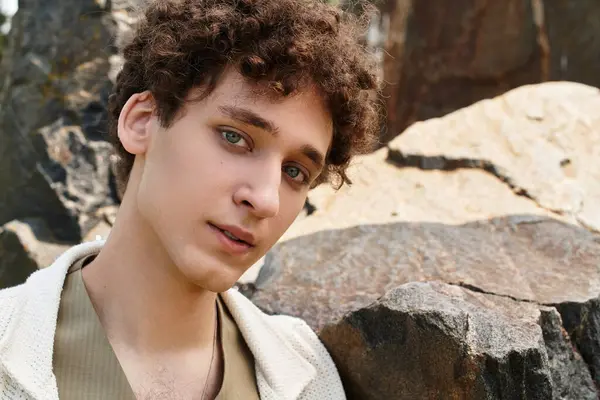 A young man with curly hair showcases a chic summer outfit while relaxing in a lush park setting. — Stock Photo