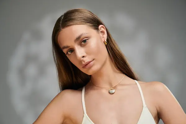 A young woman with tan skin displays effortless beauty in a studio against a grey background. — Stock Photo