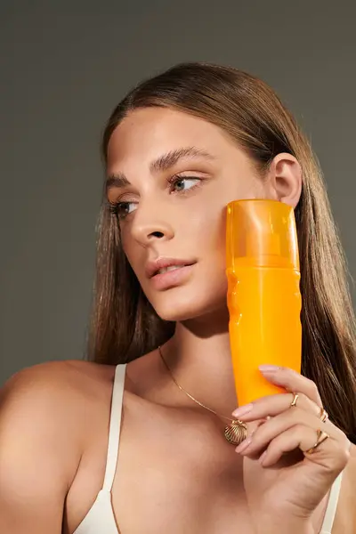 A young woman with tan skin highlights her summer beauty with sunscreen in a chic studio. — Stock Photo