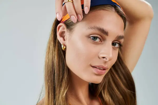 A young woman poses elegantly in a studio, highlighting her summer outfit and natural makeup. — Stock Photo