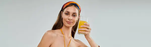 A confident young woman with tan skin enjoys a cool juice, showcasing summer fashion in a studio. — Stock Photo
