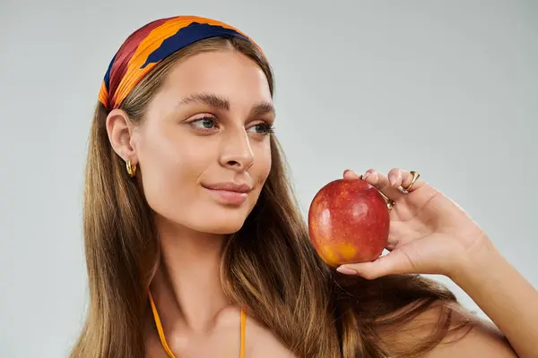 A young woman in a summer outfit poses gracefully while holding a fresh apple, showcasing her style. — Stock Photo